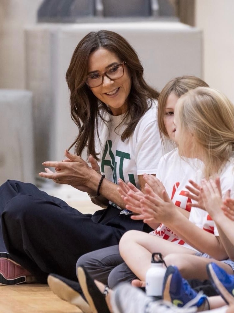 Queen Mary smiling and playing tag with children on the gym floor at Østerbrohuset in Copenhagen — Photo: Kongehuset