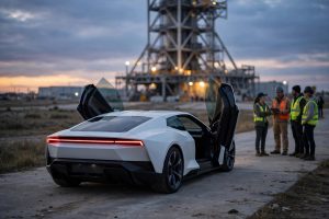 White Tesla Roadster sports car with butterfly doors open at a Texas rocket test facility at dusk