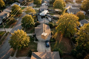 Editorial photograph of a Wing delivery drone hovering over a suburban home and lowering a package on a tether for Walmart drone delivery